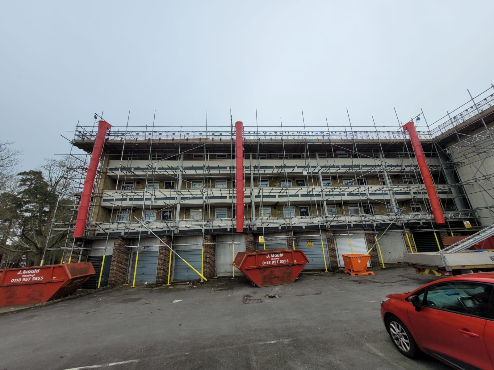 Residential block scaffolding with three red debris chutes